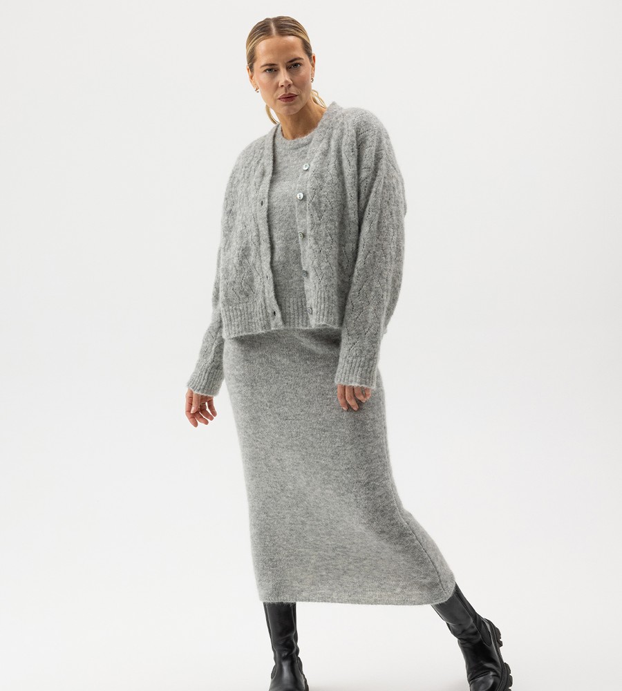 Flera stickade plagg som hänger på galge på en klädställning