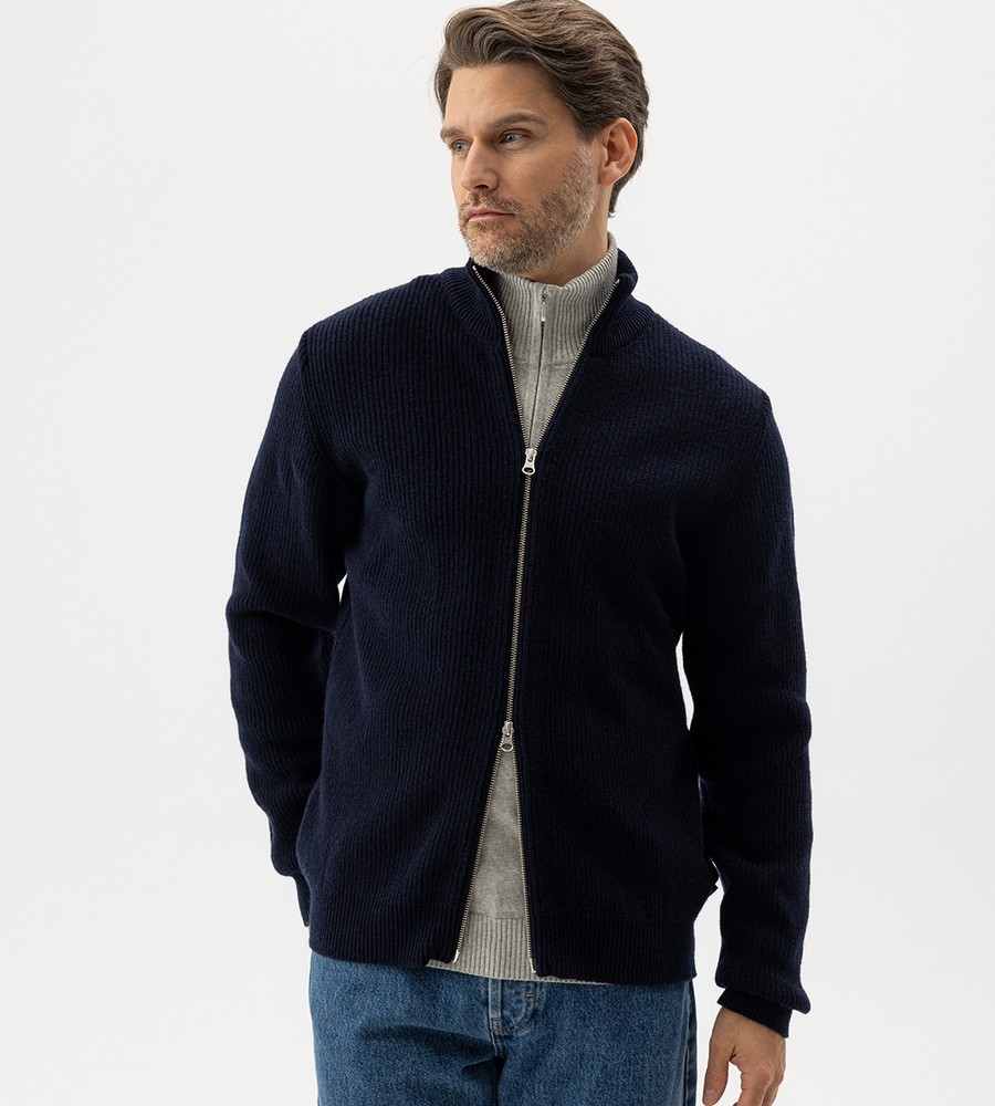 Flera stickade plagg som hänger på galge på en klädställning