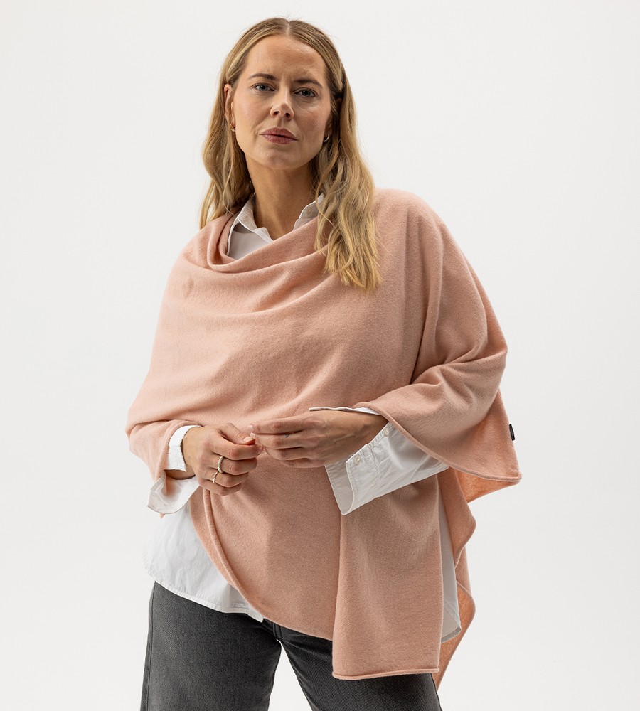 Flera stickade plagg som hänger på galge på en klädställning