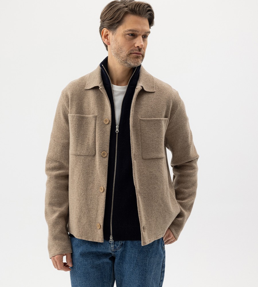 Flera stickade plagg som hänger på galge på en klädställning