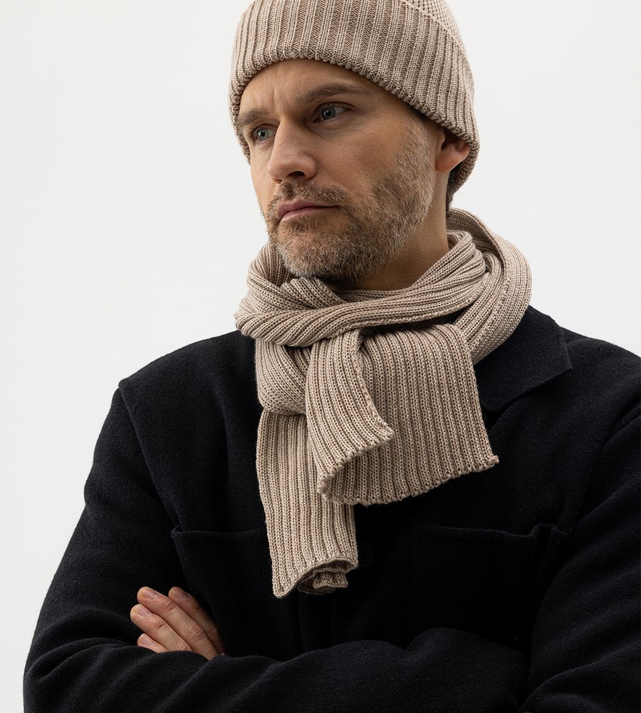 Flera stickade plagg som hänger på galge på en klädställning