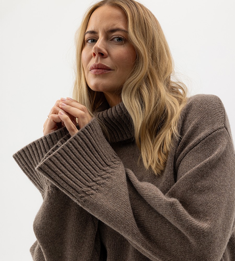 Flera stickade plagg som hänger på galge på en klädställning