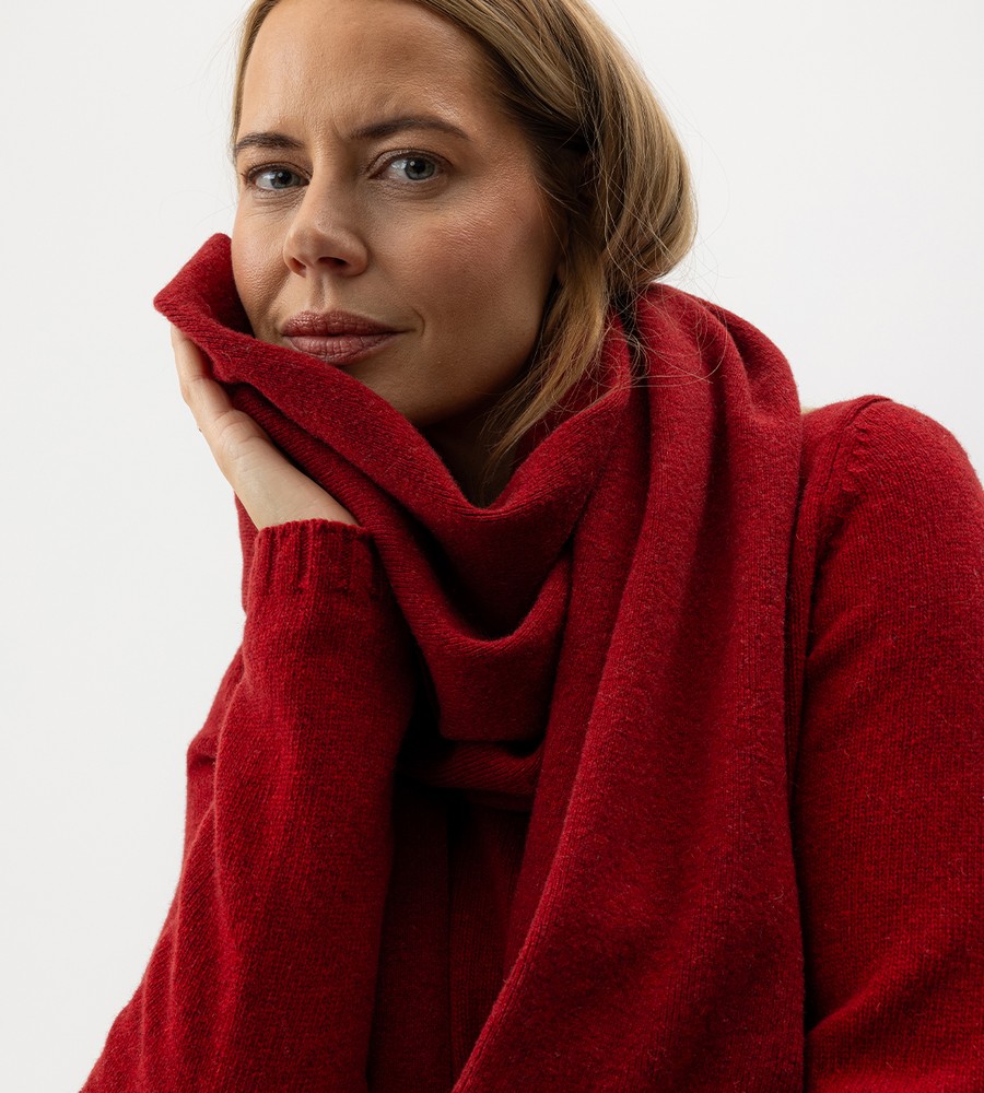 Flera stickade plagg som hänger på galge på en klädställning