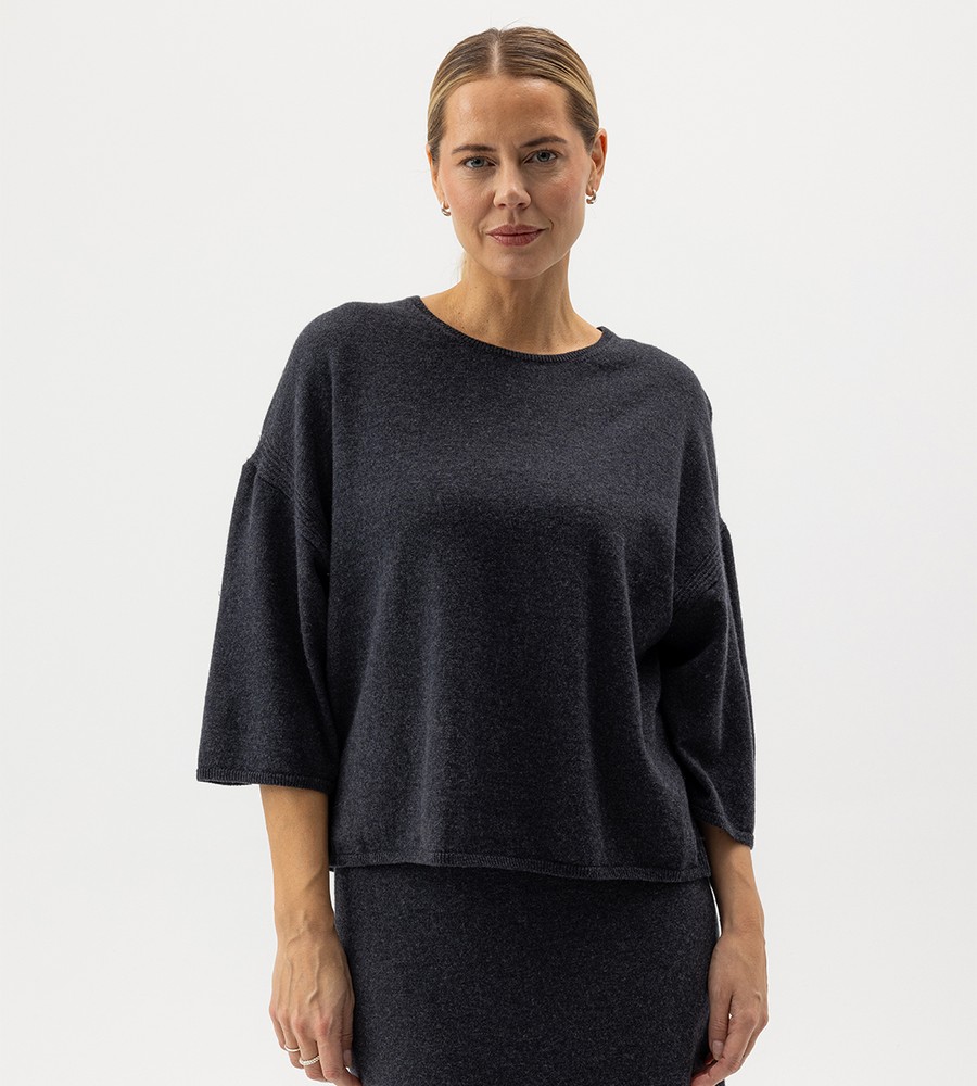 Flera stickade plagg som hänger på galge på en klädställning