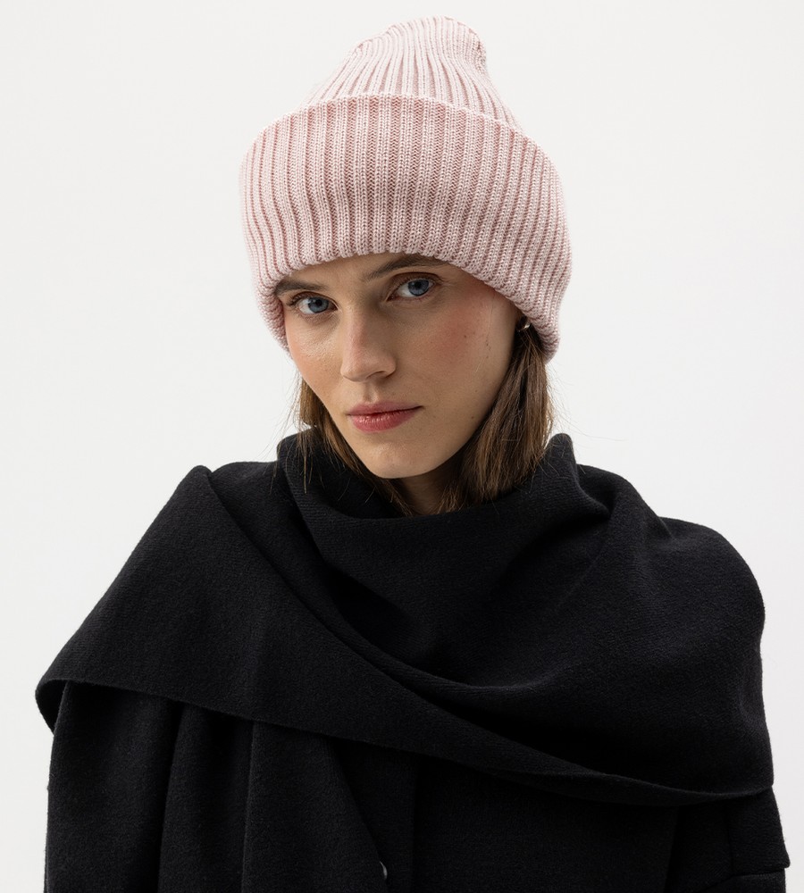 Flera stickade plagg som hänger på galge på en klädställning