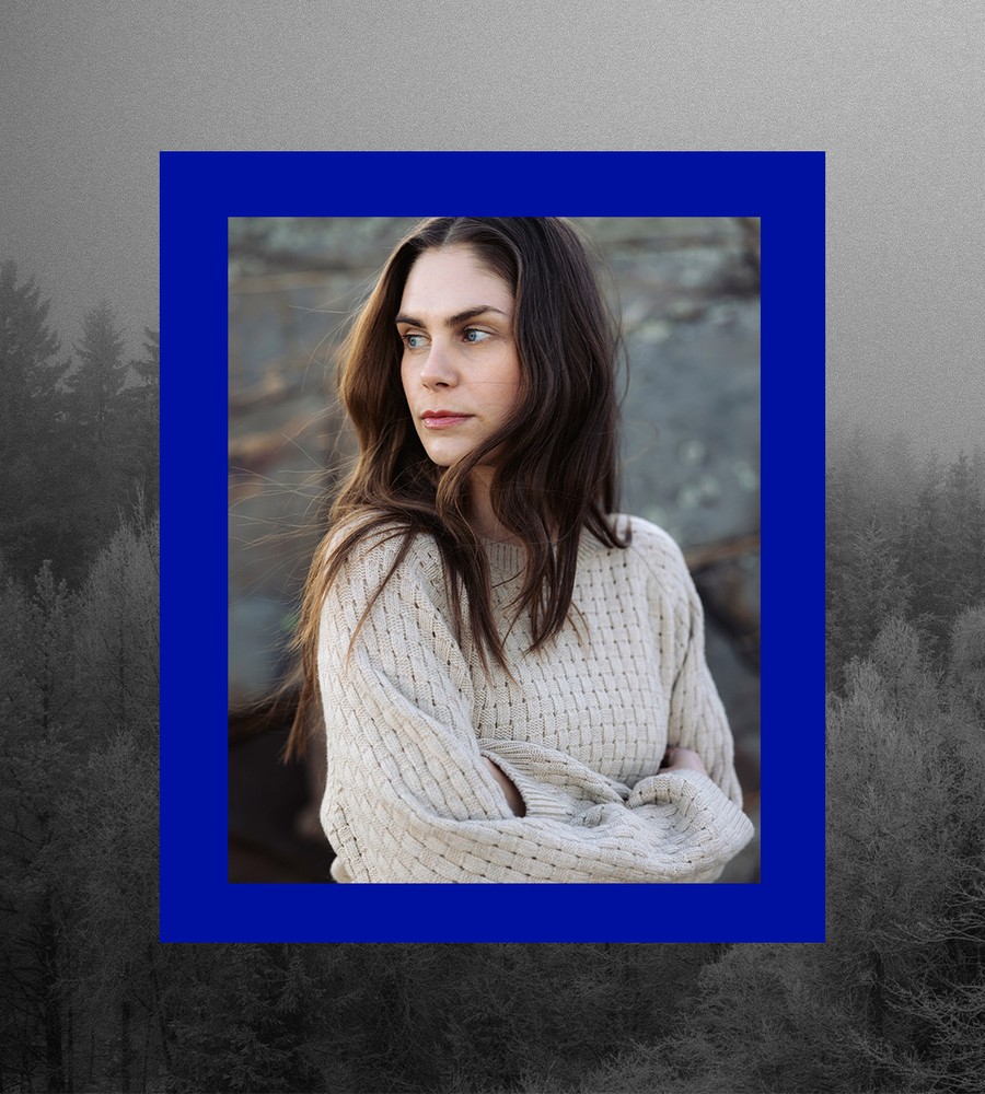 Kvinna går längst med havet i gräset och bär linneplagg