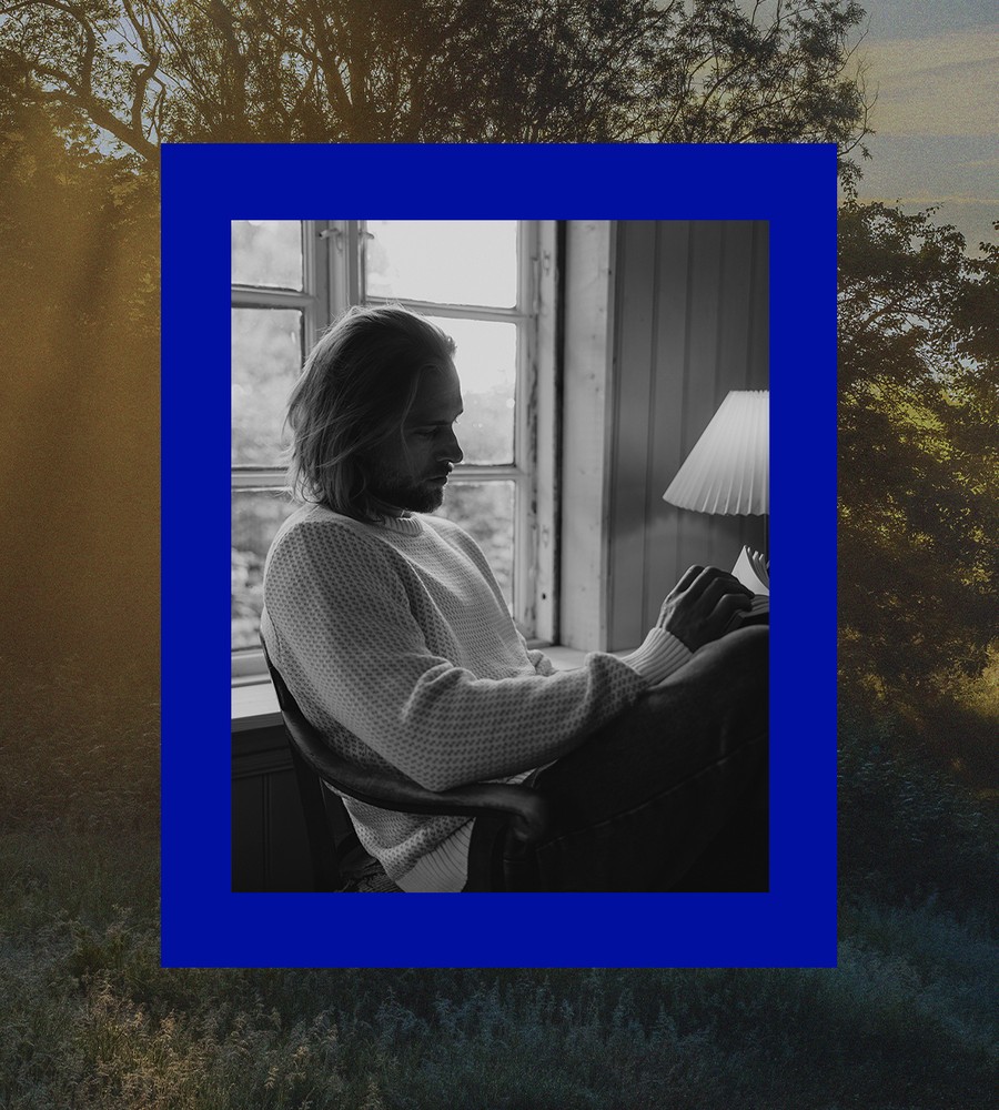 Kvinna går längst med havet i gräset och bär linneplagg