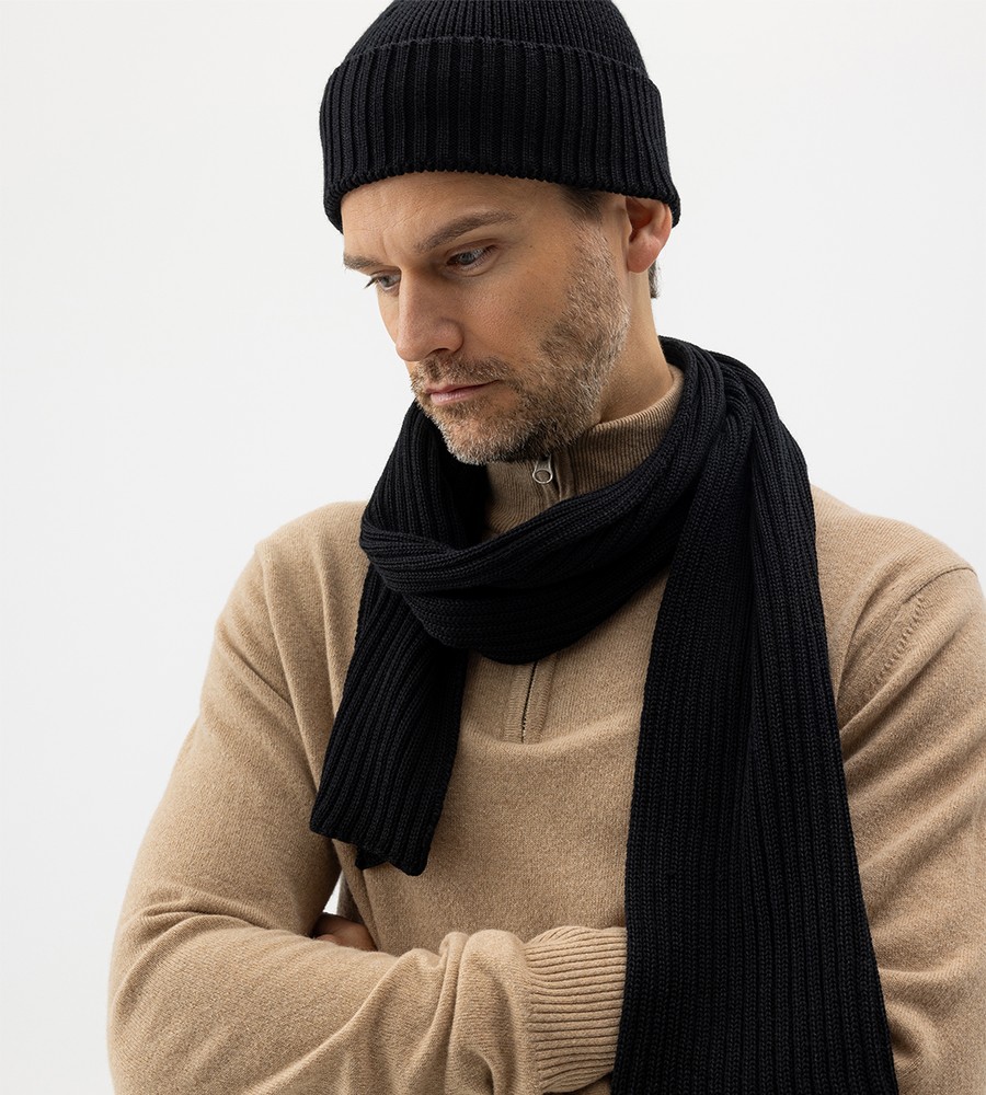 Flera stickade plagg som hänger på galge på en klädställning