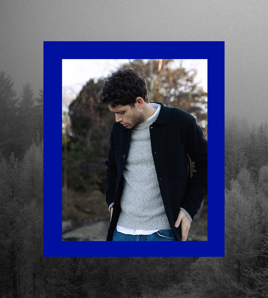 Kvinna går längst med havet i gräset och bär linneplagg