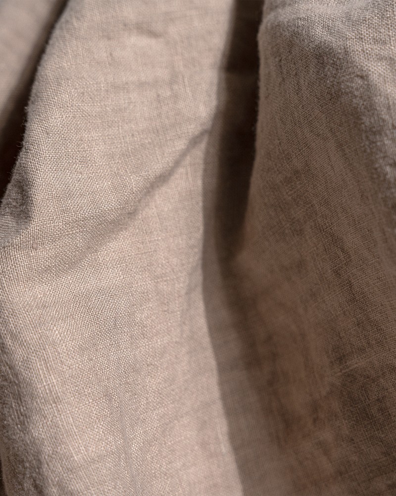 Kvinna och man går längst med strandkanten och bär linneplagg