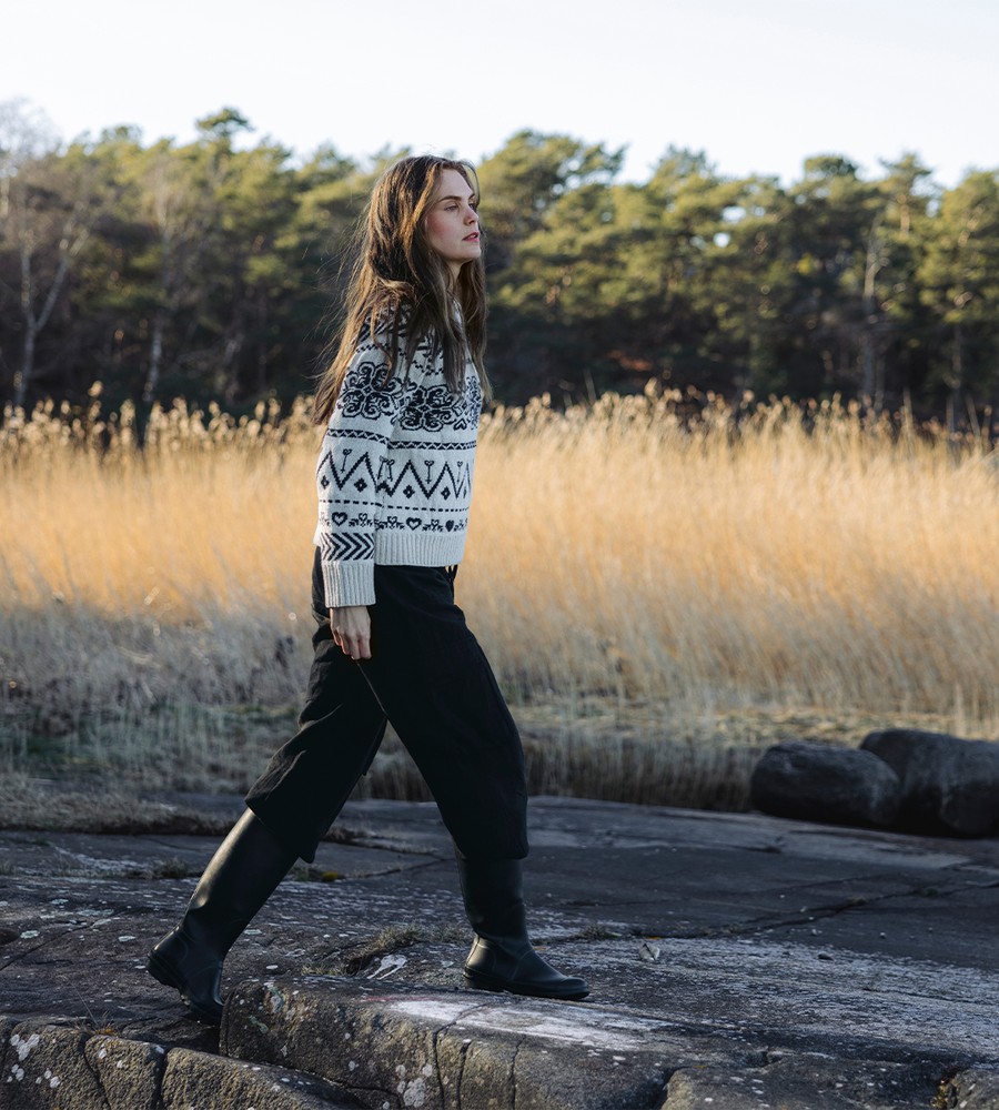 Flera stickade plagg som hänger på galge på en klädställning