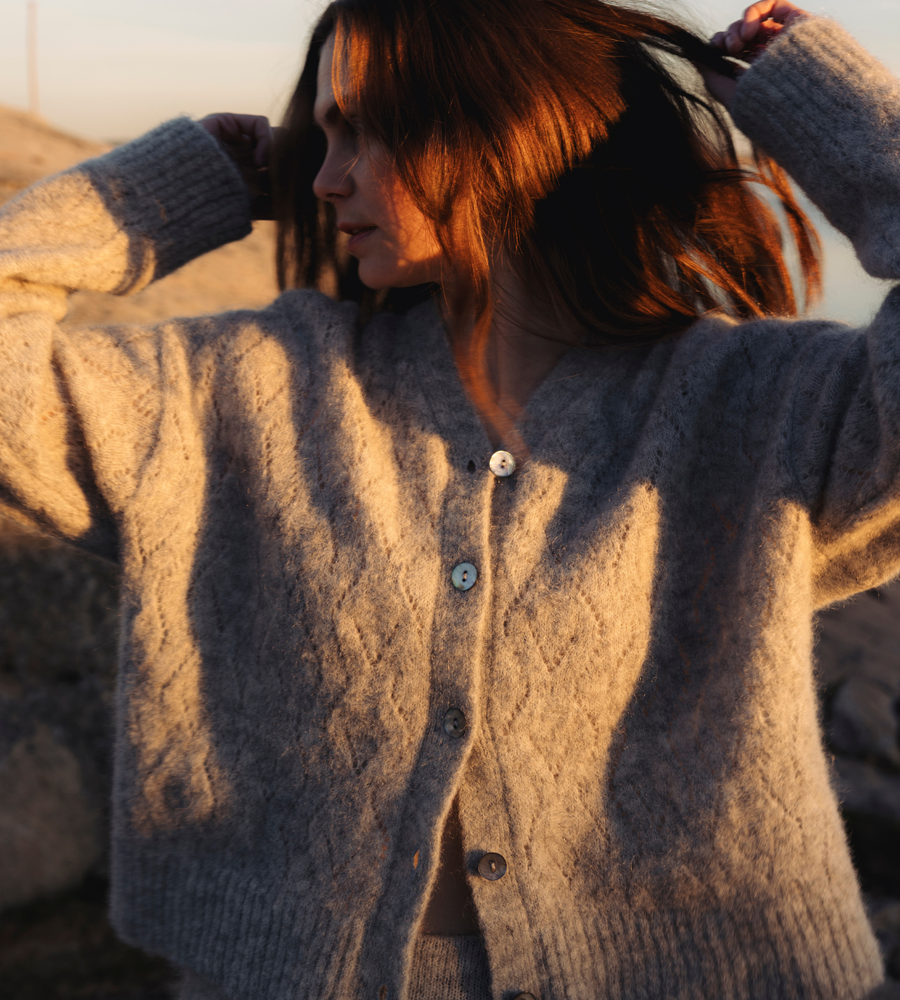 Flera stickade plagg som hänger på galge på en klädställning