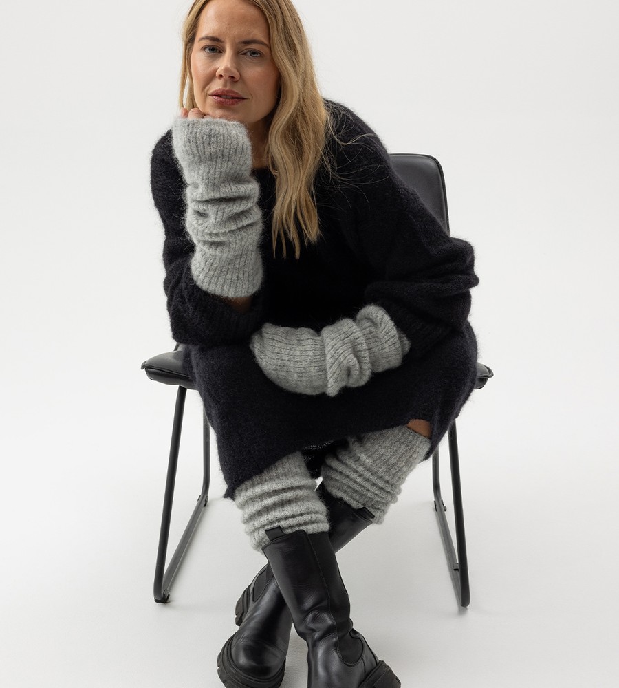 Flera stickade plagg som hänger på galge på en klädställning