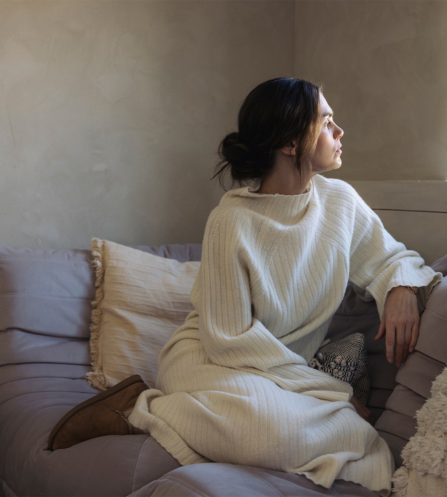 Flera stickade plagg som hänger på galge på en klädställning