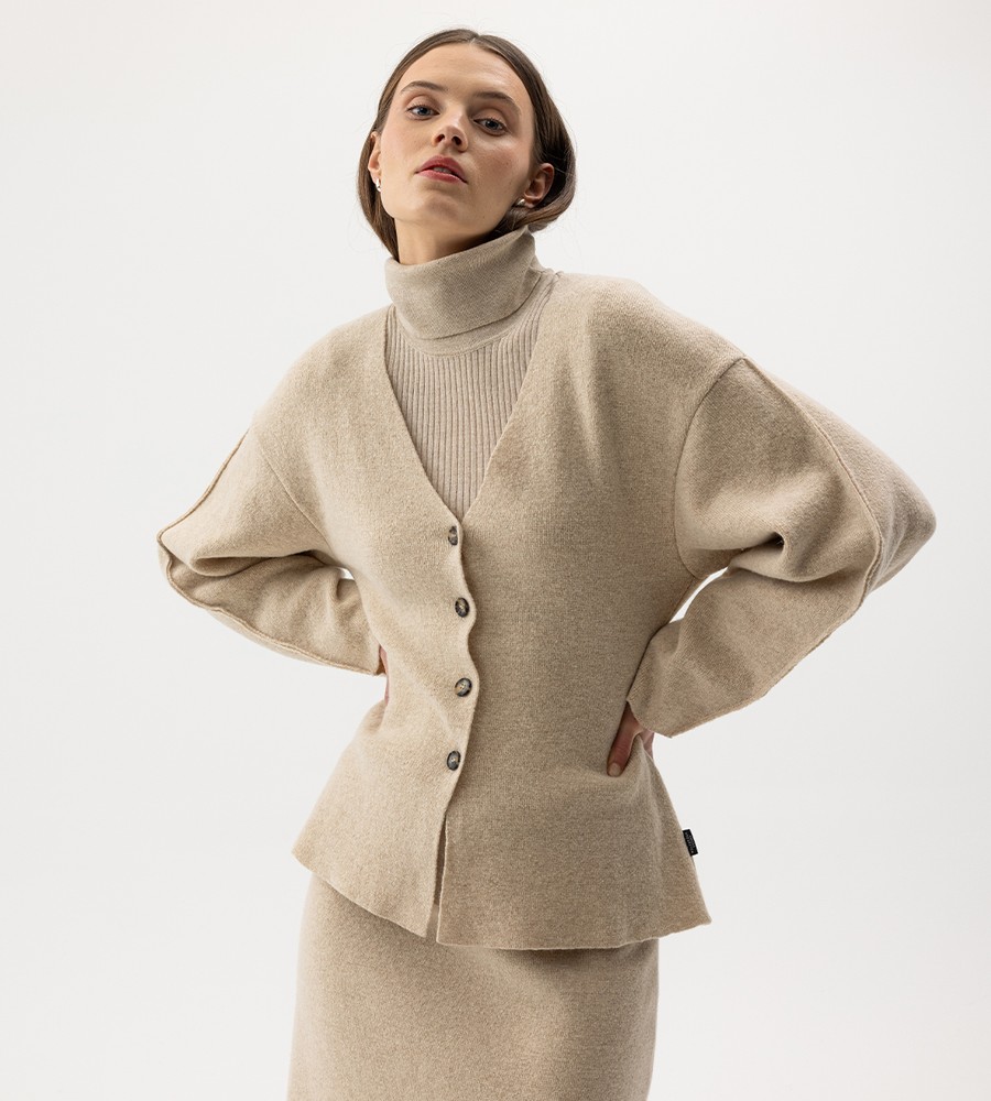 Flera stickade plagg som hänger på galge på en klädställning