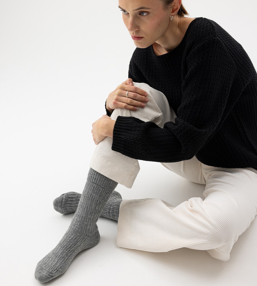 Flera stickade plagg som hänger på galge på en klädställning