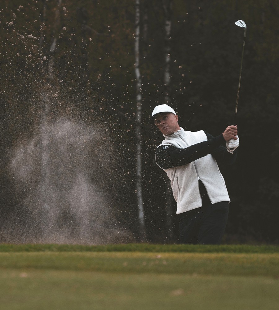 Flera stickade plagg som hänger på galge på en klädställning