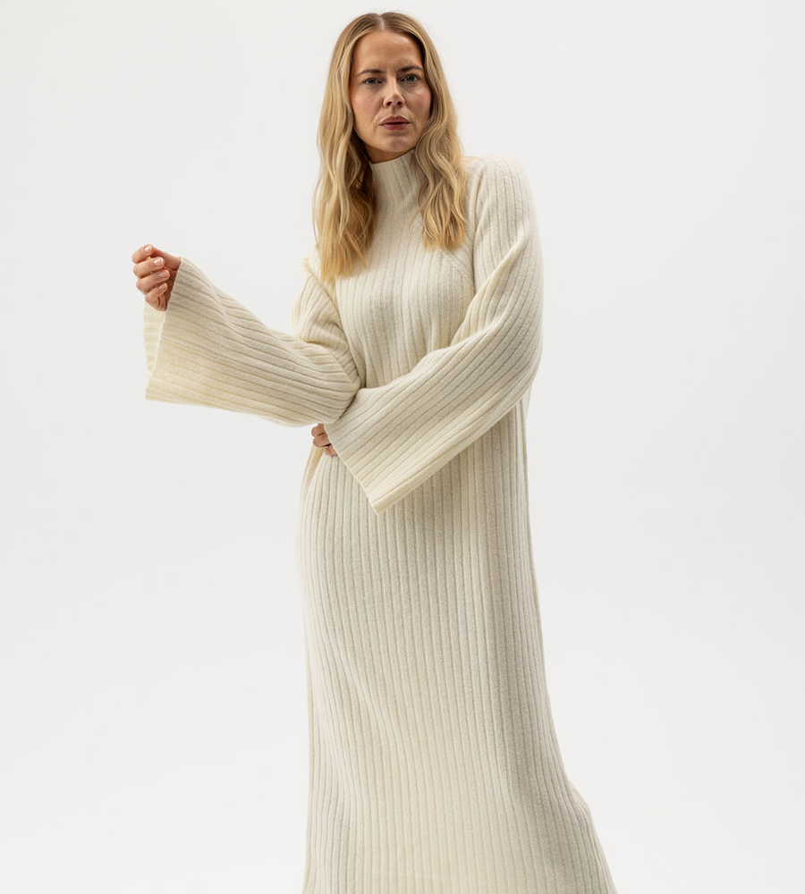 Flera stickade plagg som hänger på galge på en klädställning