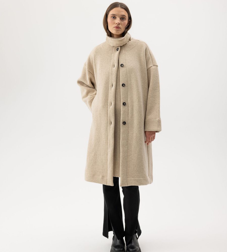 Flera stickade plagg som hänger på galge på en klädställning