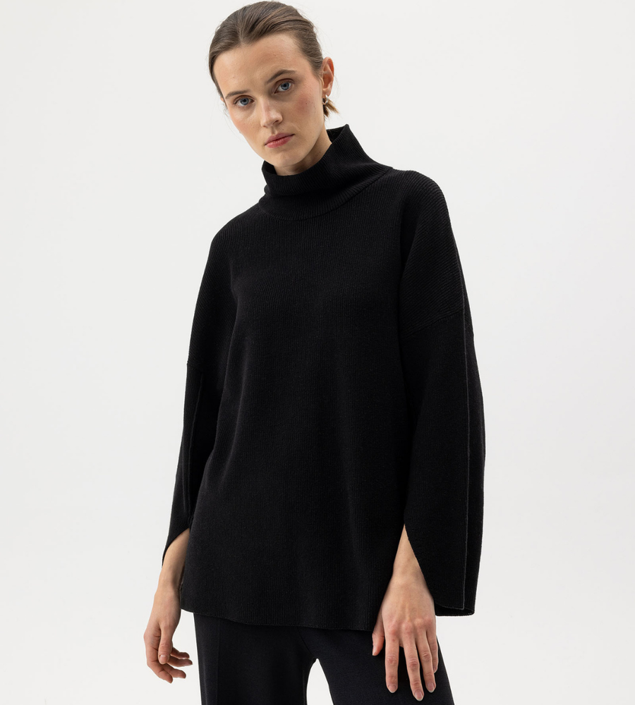 Flera stickade plagg som hänger på galge på en klädställning