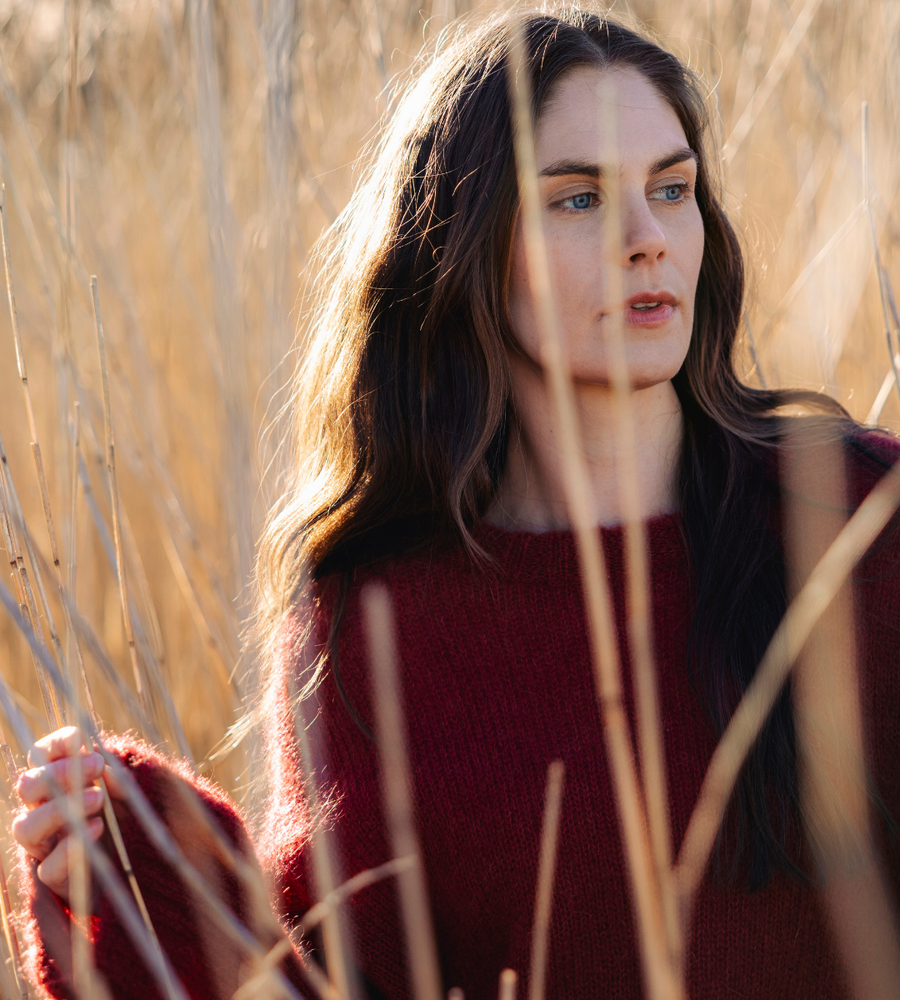 Flera stickade plagg som hänger på galge på en klädställning