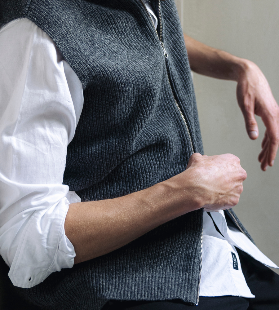 Flera stickade plagg som hänger på galge på en klädställning