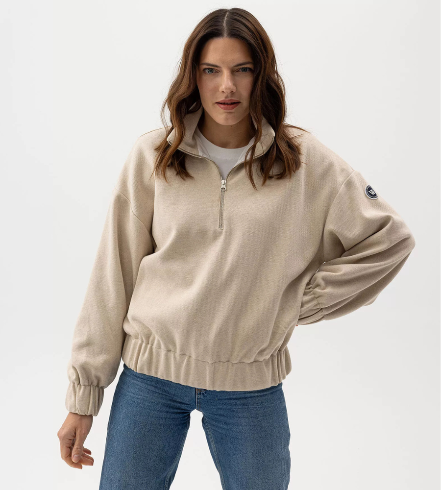 Flera stickade plagg som hänger på galge på en klädställning