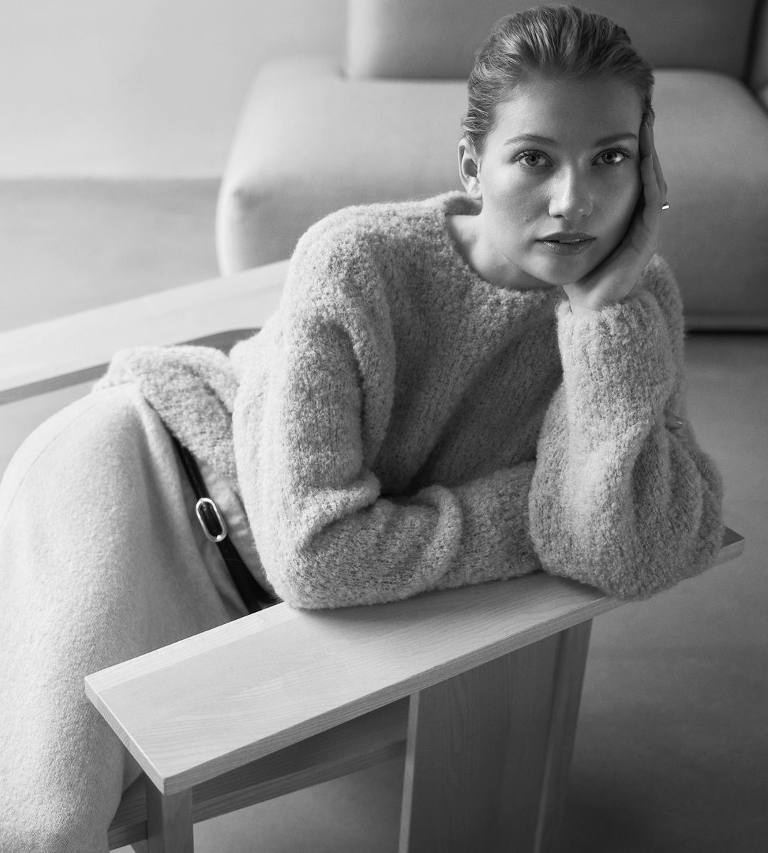 Tjej med stickad tröja som lutar sig mot armstöd