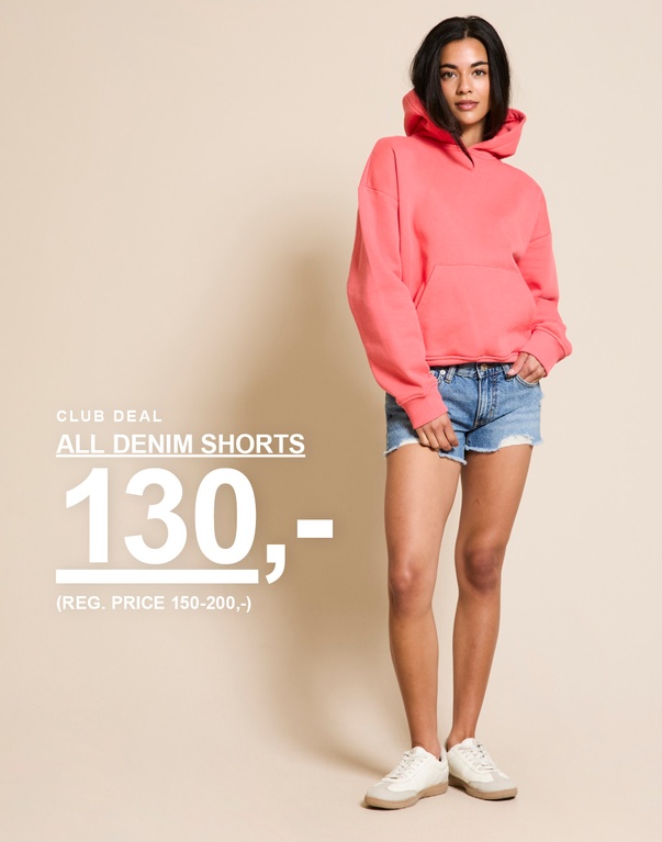 Jente i denimshorts og korallfarget hettegenser. Kampanjetekst: "CLUB DEAL, DENIMSHORTS, 80,- (FAST PRIS 150,-)".