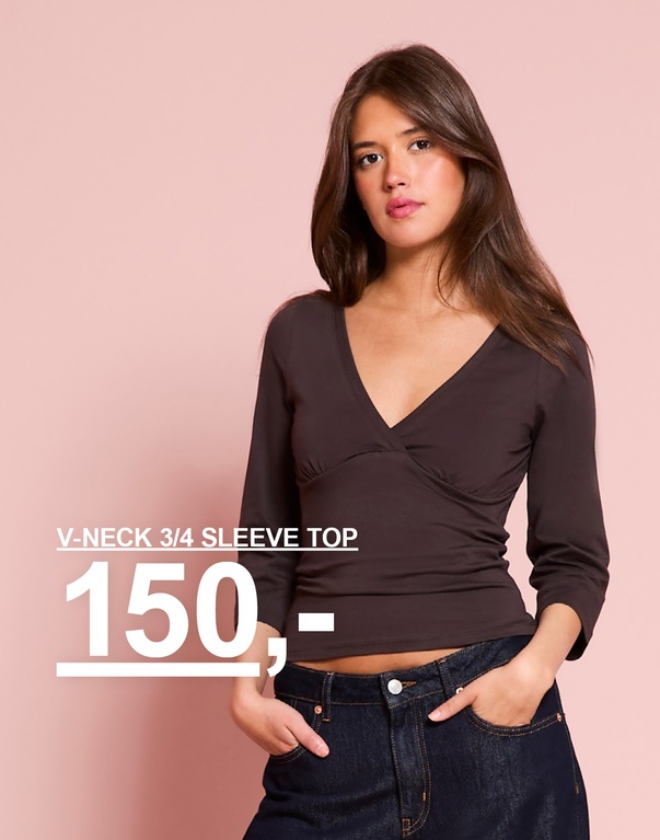 Jente i brun topp med V-hals og 3/4-ermer, stylet med mørke jeans. Kampanjetekst: "V-NECK 3/4 SLEEVE TOP, 150,-".