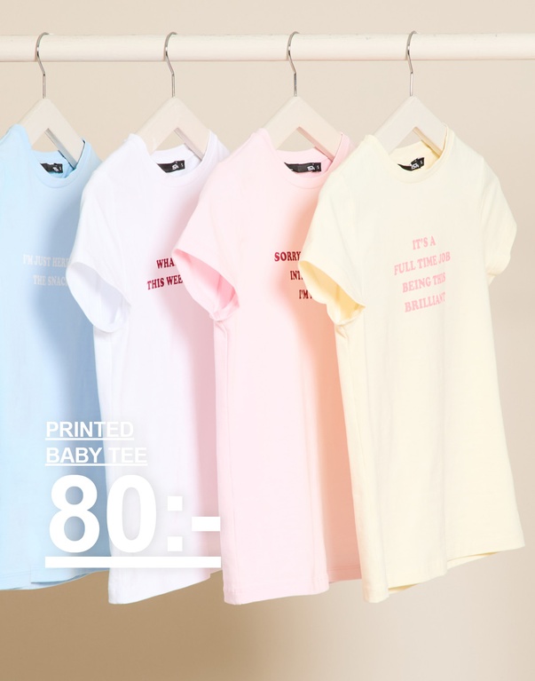 Printade t-shirts i ljusblå, vit, ljusrosa och ljusgul. Kampanjtext: "PRINTED BABY TEE, 80:-".