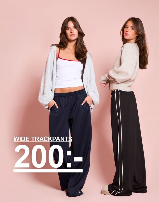 Tre tjejer i vida trackpants i brunt och mörkblått, stylade med toppar och stickade plagg. Kampanjtext: "WIDE TRACKPANTS 200:-"