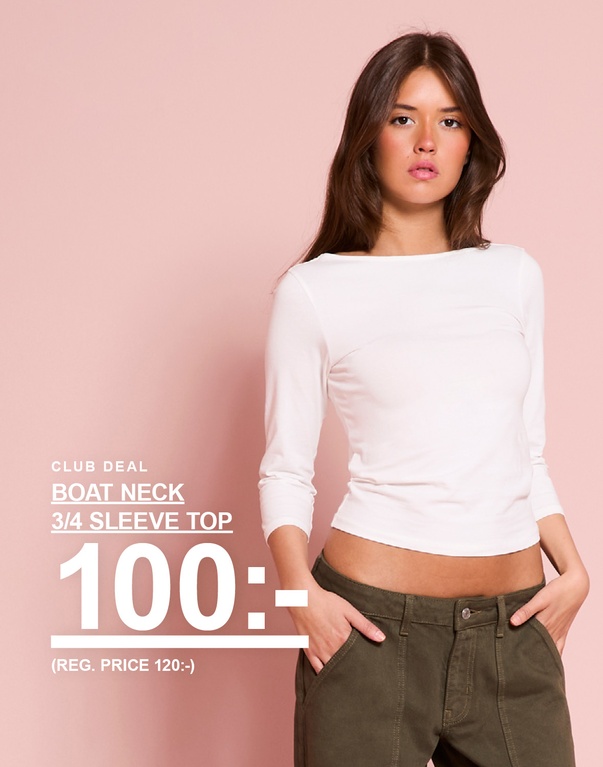 Modell bär vit topp med trekvartsärm och båtringning. CLUB DEAL – BOAT NECK 3/4 SLEEVE TOP 100:- (REG. PRICE 120:-).