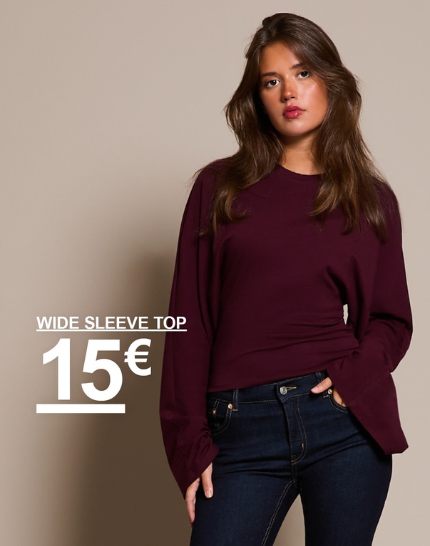 "Mädchen in burgunderfarbenem Top mit weiten Ärmeln und dunkelblauer Jeans. Kampagnentext: 'WIDE SLEEVE TOP, 15€'."