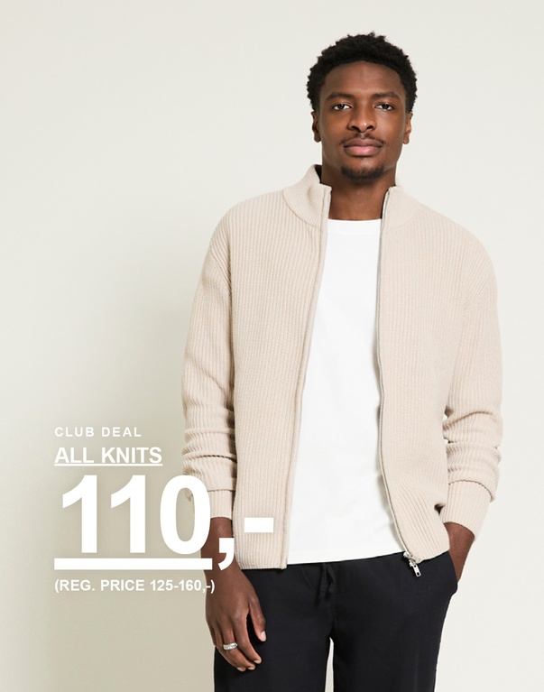 Mand i beige ribstrikket cardigan med lynlås over hvid t-shirt og sorte bukser mod lys baggrund. Club deal all knits 110,- (reg. price 125–160,-)