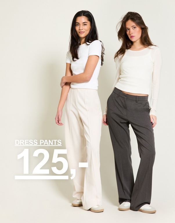 To piger i dressbukser, et par beige og et par mørkegrå. Kampagnetekst: 'DRESS PANTS, 125,-'.
