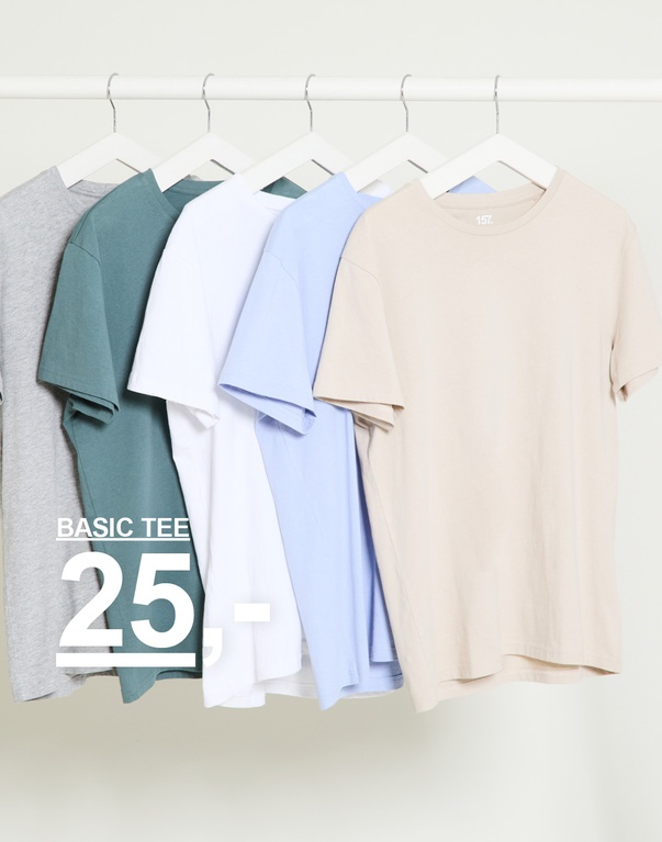 Flere ensfarvede t-shirts i grå, grøn, hvid, lyseblå og beige på bøjler mod lys baggrund. Basic tee 25,-