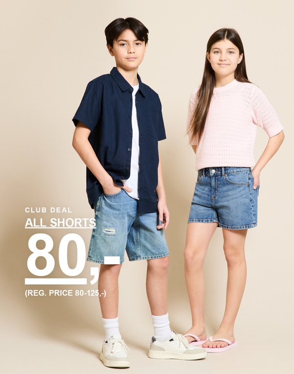 To børn i denimshorts og overdele i farverne blå og lyserød foran en lys baggrund. CLUB DEAL ALL SHORTS 80,- (REG. PRICE 80-125,-)