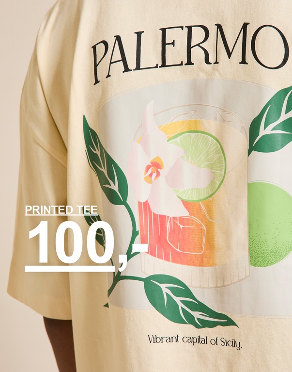 Beige t-shirt med “PALERMO”-tekst og farverigt print af drink med blomst og lime foran beige baggrund. PRINTED TEE 100,-