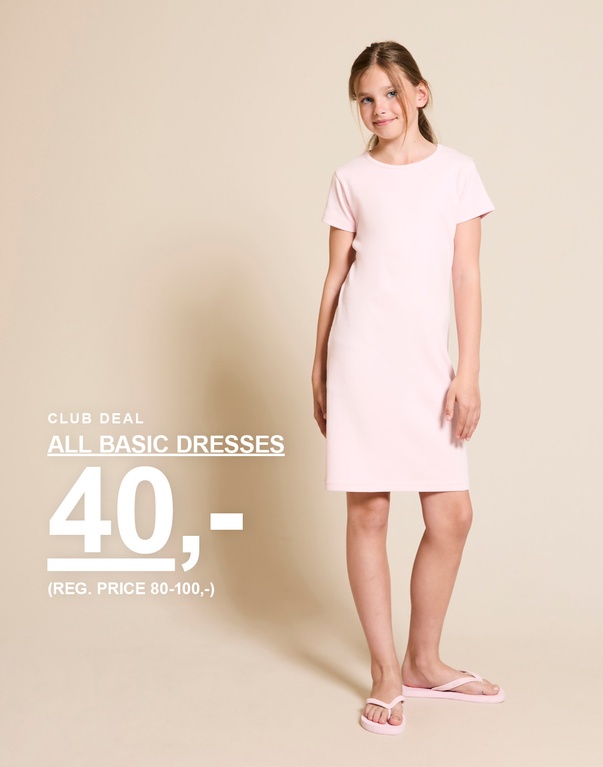 Pige står foran en lys baggrund iført en lyserød basis kjole og matchende klipklappere. CLUB DEAL ALL BASIC DRESSES 40,- (REG. PRICE 80-100,-)  Sommershorts