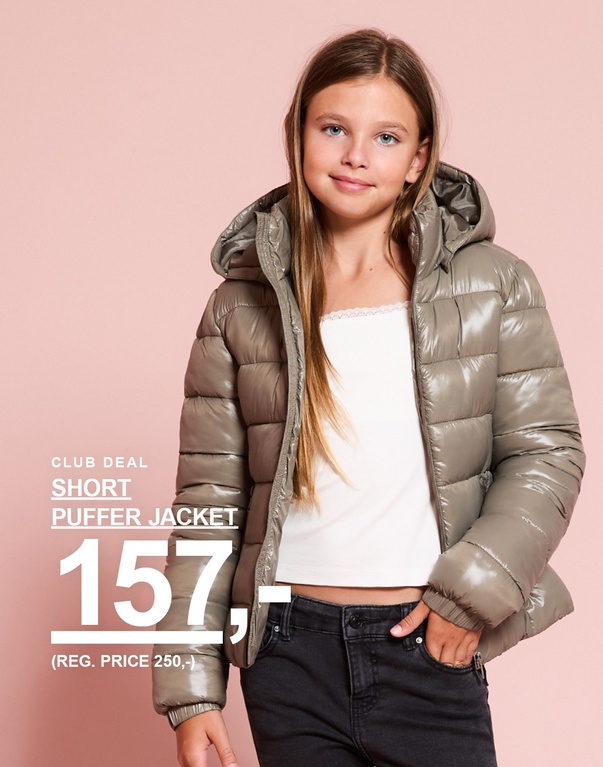 Pige i en kort, grøn pufferjakke foran en lyserød baggrund. Club Deal: Short Puffer Jacket 157,- (førpris 250,-).