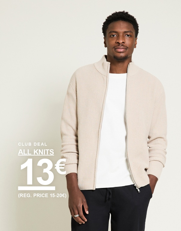 Mies beigenvärisessä ribbineuletakissa vetoketjulla, valkoinen t-paita ja mustat housut, vaaleaa taustaa vasten. Club deal all knits 13€ (reg. price 15–20€)
