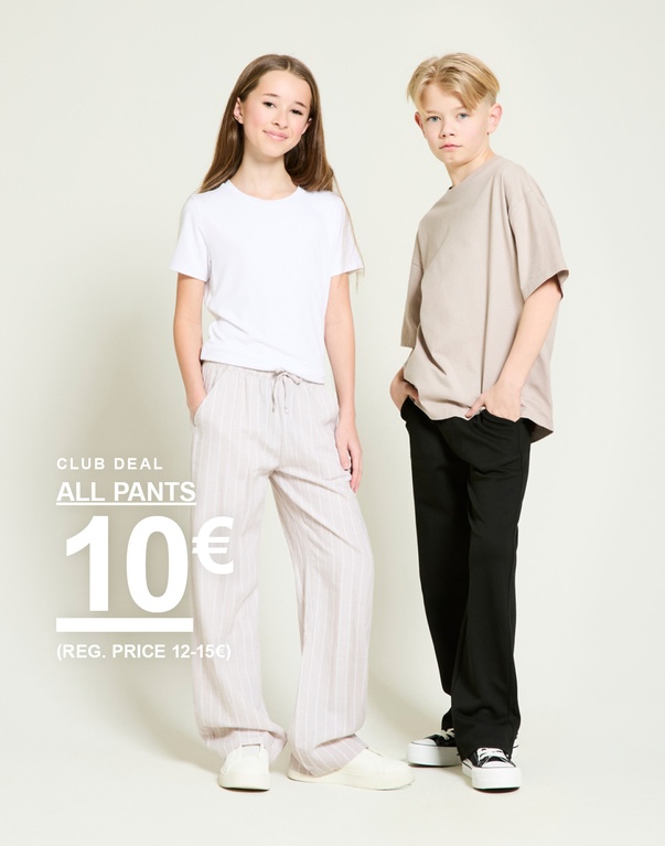 Mädchen in gestreifter Hose und weißem T-Shirt sowie Junge in beigem T-Shirt und schwarzer Hose vor hellem Hintergrund. SPRING 2026 CLUB DEAL ALL PANTS 10€ (REG. PRICE 12-15€)