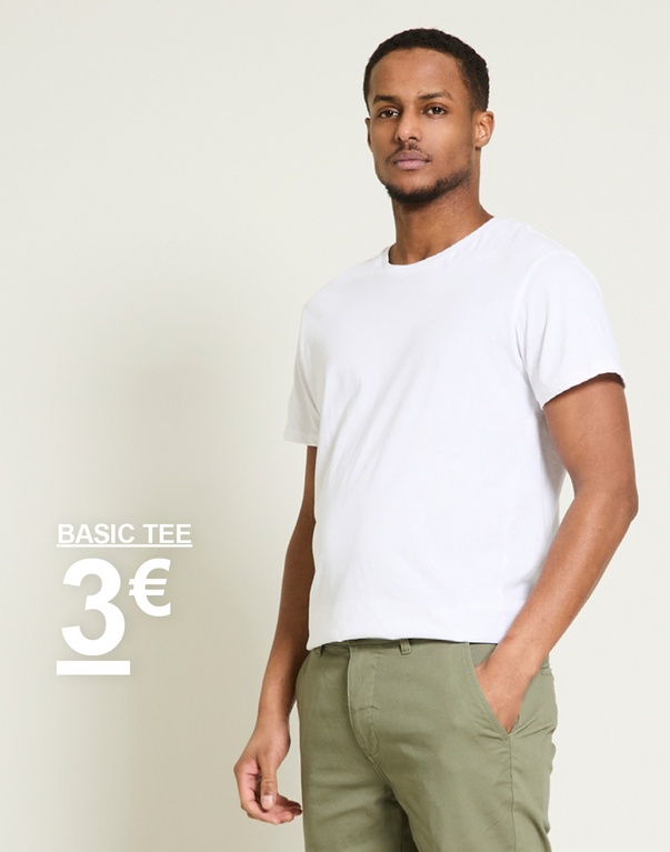 Mies valkoisessa basic tee -t-paidassa ja vihreissä housuissa vaaleaa taustaa vasten. Basic tee 3€