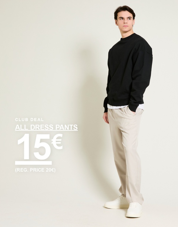 Mann in schwarzem Sweatshirt mit beigen Anzughosen und weißen Sneakern vor hellem Hintergrund. Club deal. All dress pants 15€ (Reg. price 20€)