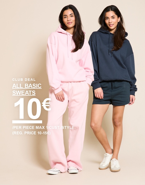 Vrouw in wijde zachte broek in offwhite en een roze top. Campagnetekst: 'CLUB DEAL, LOOSE SOFT PANTS, 13€ (NORMALE PRIJS 15€)'.