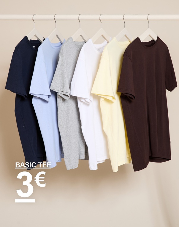 Basic T-shirts in verschillende kleuren hangen aan kledinghangers voor een beige achtergrond. BASIC TEE 3€