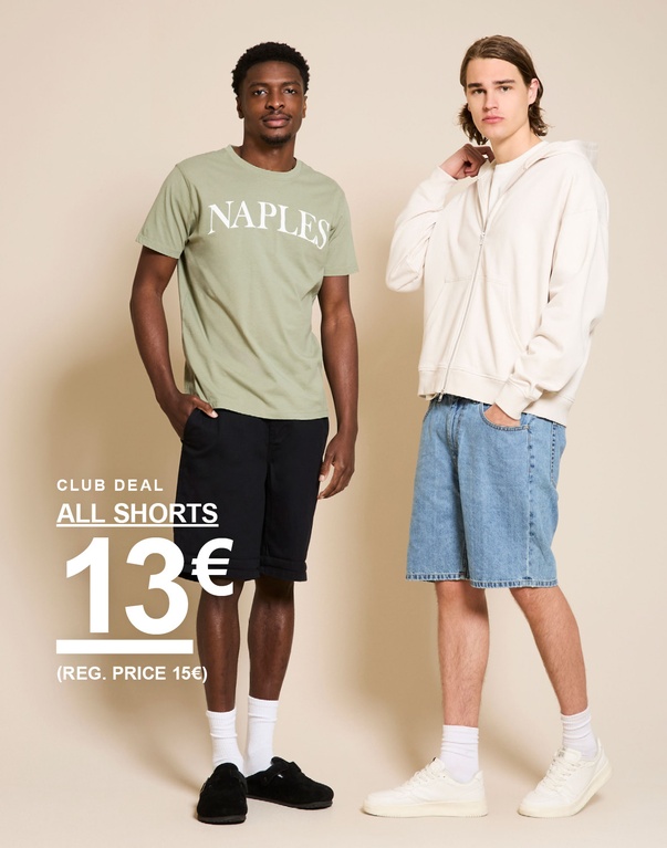 Twee mannen in shorts – één met een groene “NAPLES”-T-shirt en donkere shorts, de ander met een beige hoodie en lichte denim shorts voor een beige achtergrond. CLUB DEAL. ALL SHORTS 13€ (REG. PRICE 15€)