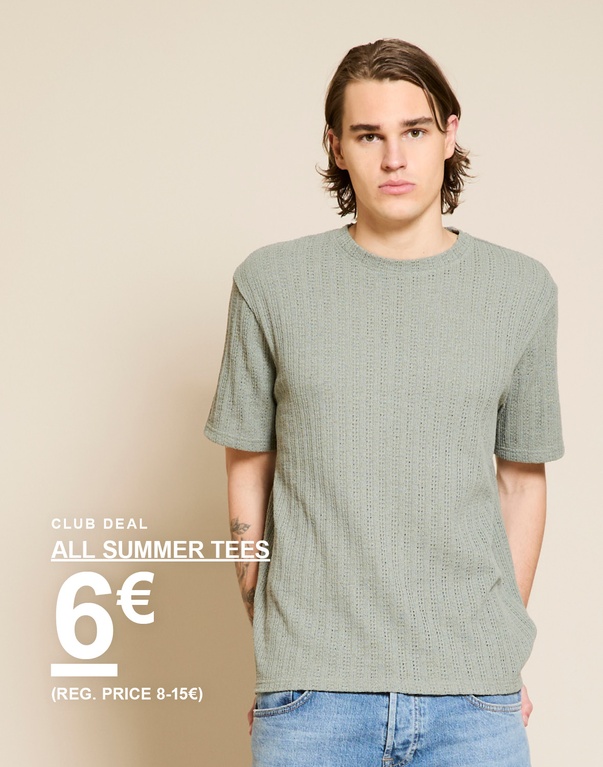 Mann in hellgrünem Strick-T-Shirt und hellblauen Jeans vor beigem Hintergrund. CLUB DEAL. ALL SUMMER TEES 6€ (REG. PRICE 8-15€)