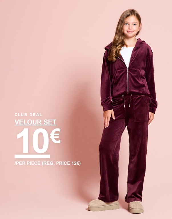 Ein Mädchen trägt ein bordeauxrotes Velours-Set mit Kapuzenjacke und Hose. CLUB DEAL – VELOUR SET 10 € / PER PIECE (REG. PRICE 12 €).